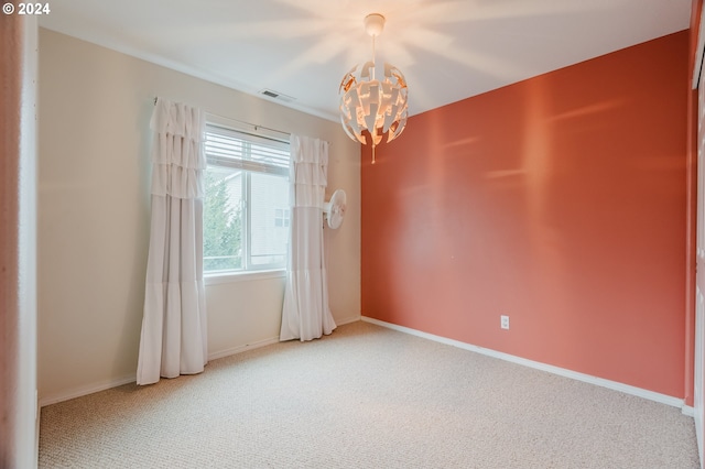 carpeted empty room featuring a chandelier