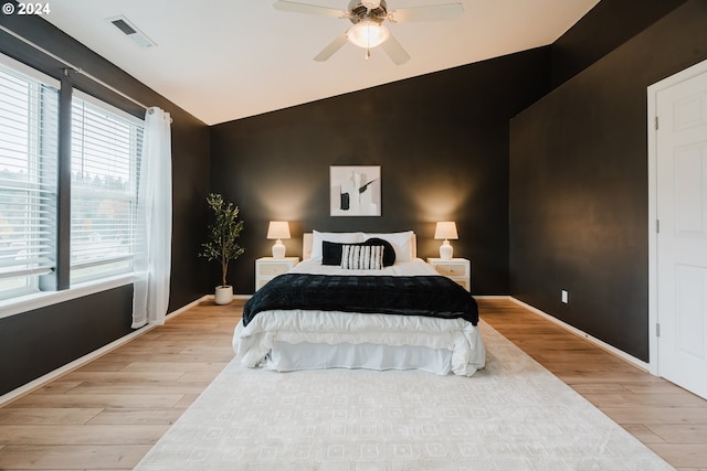 bedroom with light hardwood / wood-style flooring, vaulted ceiling, and ceiling fan