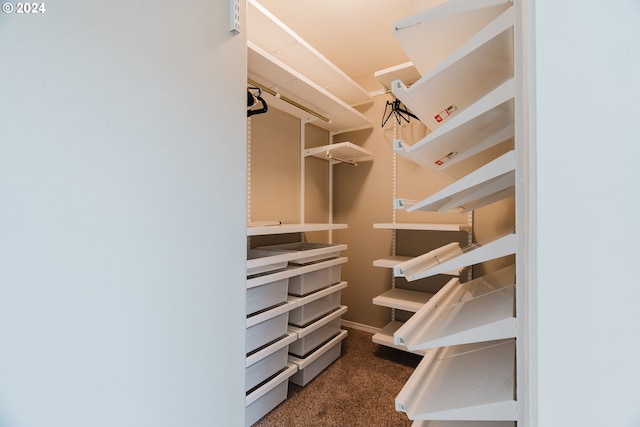 walk in closet featuring dark carpet