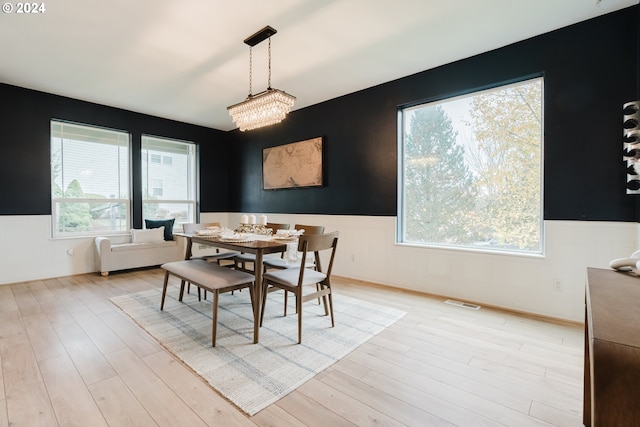 dining space featuring light wood-type flooring and a notable chandelier