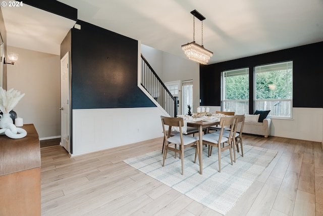 dining area with light hardwood / wood-style floors and an inviting chandelier