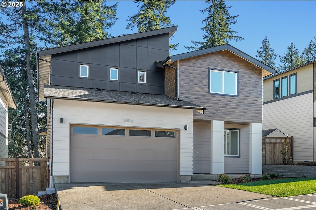 contemporary house featuring concrete driveway, an attached garage, and fence