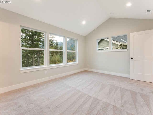 spare room featuring light colored carpet and vaulted ceiling