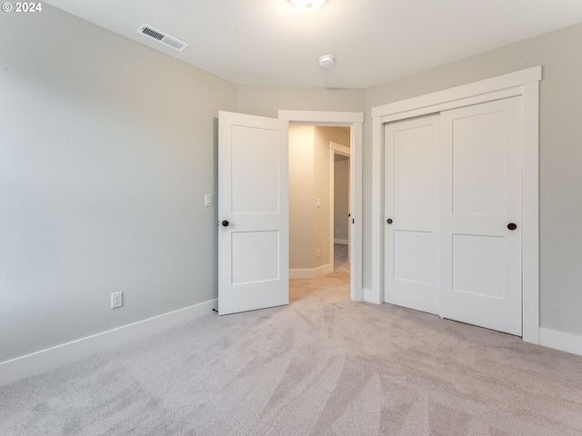 unfurnished bedroom with light colored carpet and a closet