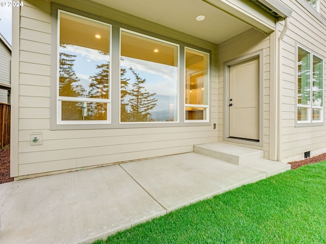 entrance to property featuring a yard and a patio area