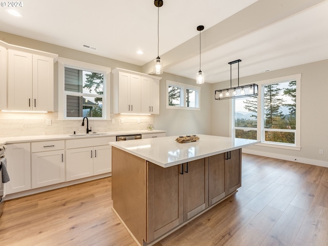 kitchen with a wealth of natural light, white cabinets, sink, and a center island