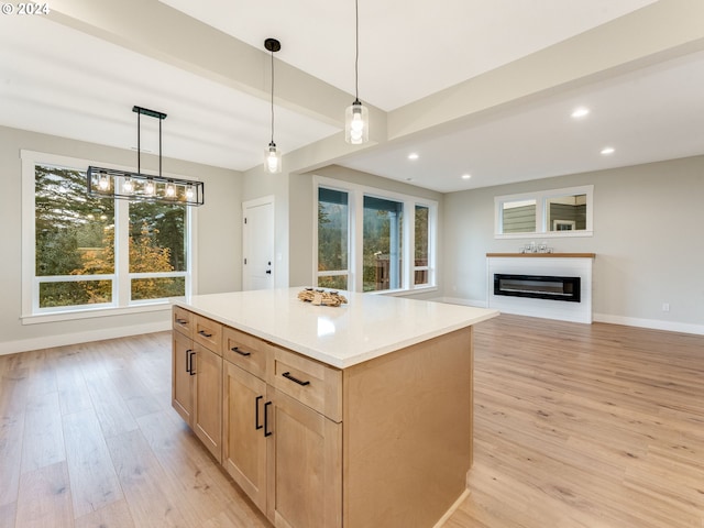 kitchen featuring beamed ceiling, light brown cabinets, hanging light fixtures, light hardwood / wood-style flooring, and a kitchen island