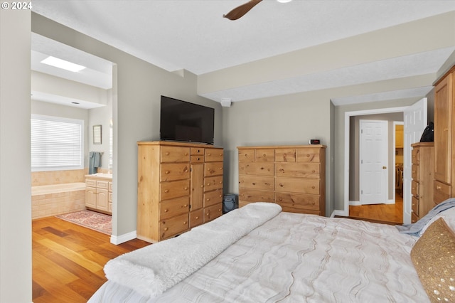 bedroom featuring ensuite bathroom, ceiling fan, and light wood-type flooring