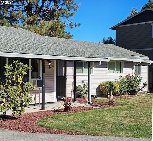 ranch-style home with a front yard and a shingled roof