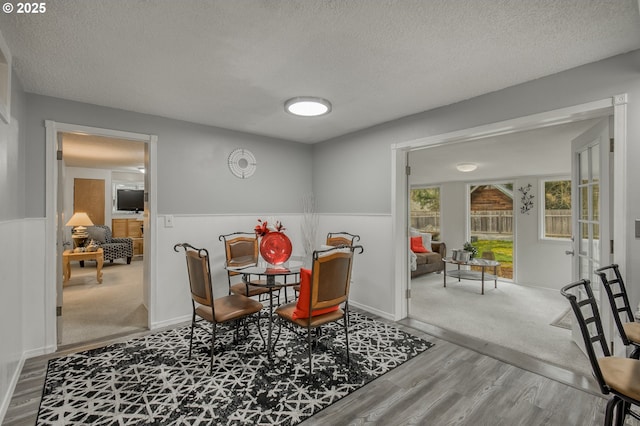 dining area featuring a wainscoted wall, a textured ceiling, and wood finished floors