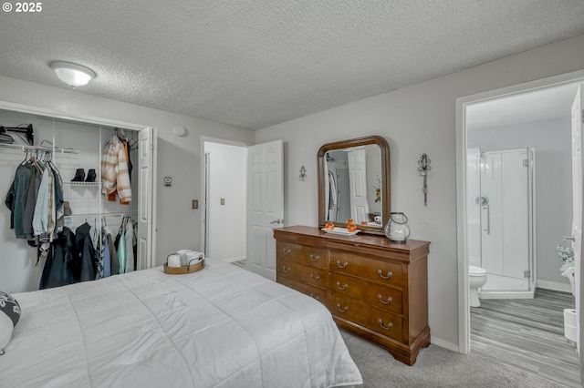 bedroom with a closet, baseboards, a textured ceiling, and ensuite bath