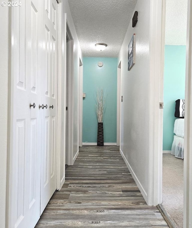 corridor featuring dark hardwood / wood-style flooring and a textured ceiling