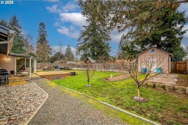 view of yard with an outbuilding, a shed, a wooden deck, and a fenced backyard