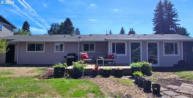 rear view of house with a yard, a deck, and roof with shingles