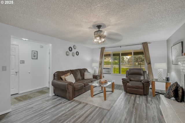 living room with a brick fireplace, a textured ceiling, and wood finished floors