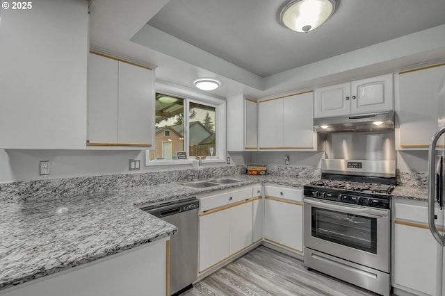 kitchen with sink, light hardwood / wood-style flooring, stainless steel appliances, light stone counters, and white cabinets