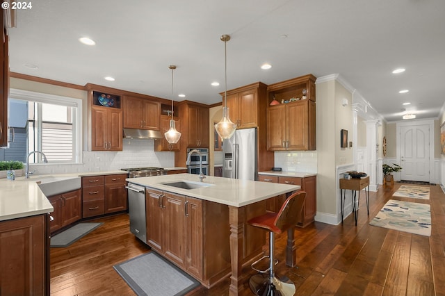 kitchen featuring appliances with stainless steel finishes, decorative light fixtures, a center island with sink, and dark wood-type flooring