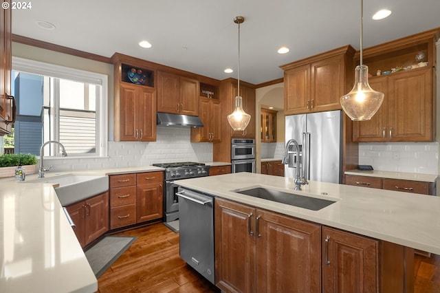 kitchen with backsplash, stainless steel appliances, sink, and hanging light fixtures