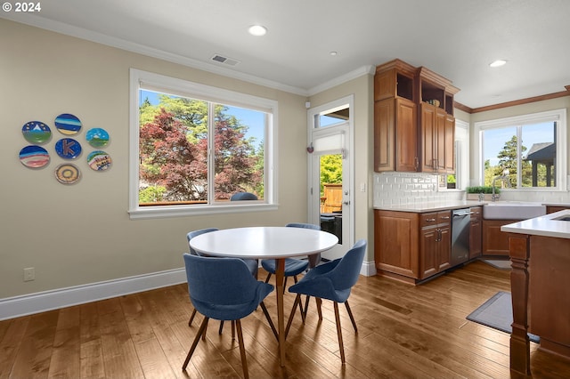 dining area with ornamental molding, dark wood-type flooring, and sink