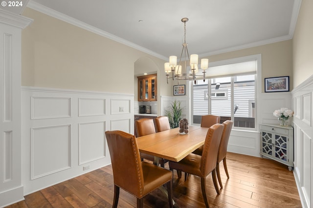 dining area with light wood-type flooring, crown molding, and an inviting chandelier