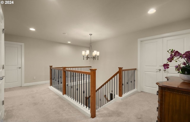 hallway featuring an inviting chandelier and light carpet