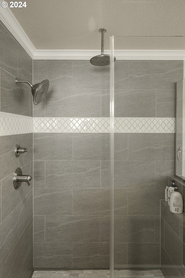 bathroom with ornamental molding and a tile shower