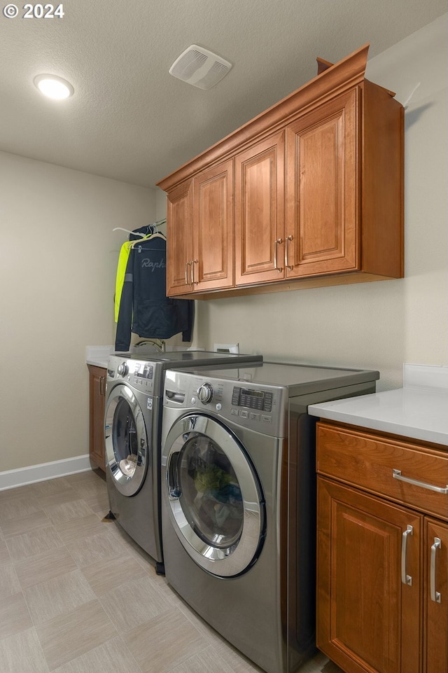 washroom featuring a textured ceiling, cabinets, and washer and dryer