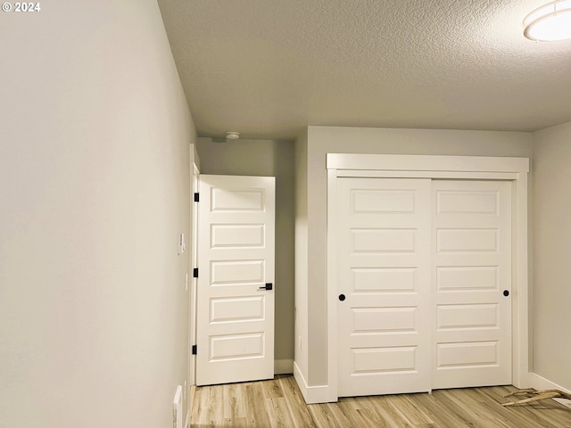 unfurnished bedroom with a textured ceiling, light hardwood / wood-style floors, and a closet