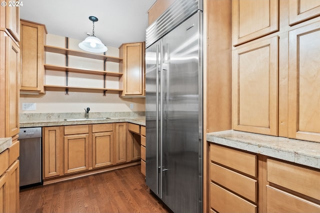 kitchen with light stone countertops, appliances with stainless steel finishes, dark hardwood / wood-style flooring, sink, and hanging light fixtures