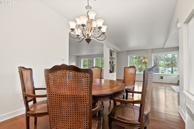 dining room featuring hardwood / wood-style floors, built in shelves, and a notable chandelier