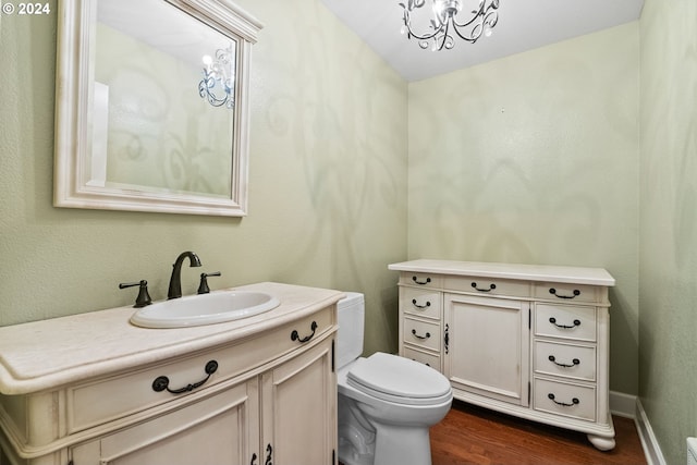 bathroom with a chandelier, vanity, hardwood / wood-style flooring, and toilet