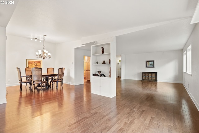 dining space featuring a notable chandelier, built in shelves, and hardwood / wood-style floors