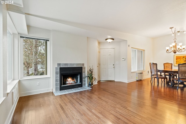 living room with hardwood / wood-style flooring, a chandelier, and a tiled fireplace