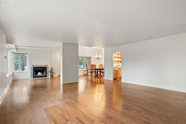 living room with hardwood / wood-style flooring, an inviting chandelier, plenty of natural light, and a tiled fireplace