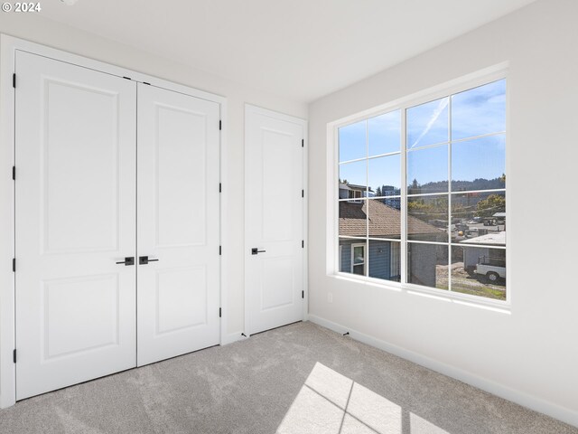 unfurnished bedroom with light carpet and a closet