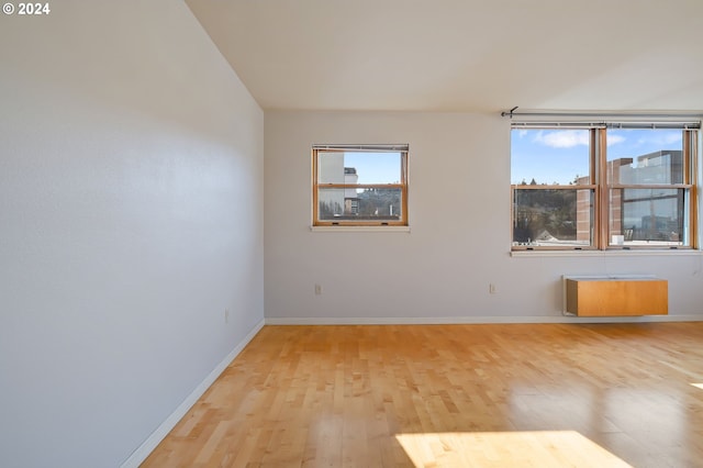 unfurnished room featuring light hardwood / wood-style floors and radiator heating unit