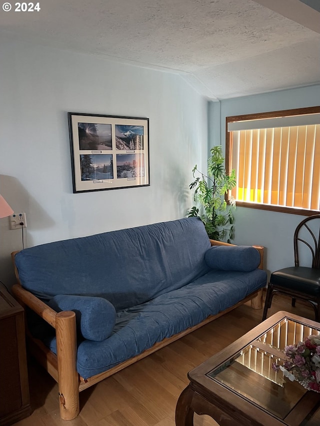 living area with a textured ceiling, wood finished floors, and lofted ceiling