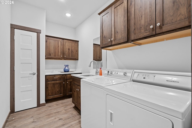 laundry area with cabinets, sink, separate washer and dryer, and light hardwood / wood-style flooring