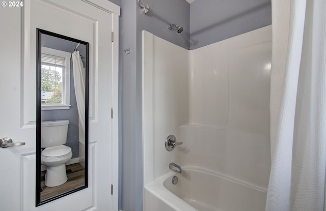 bathroom with wood-type flooring, shower / bath combo with shower curtain, and toilet