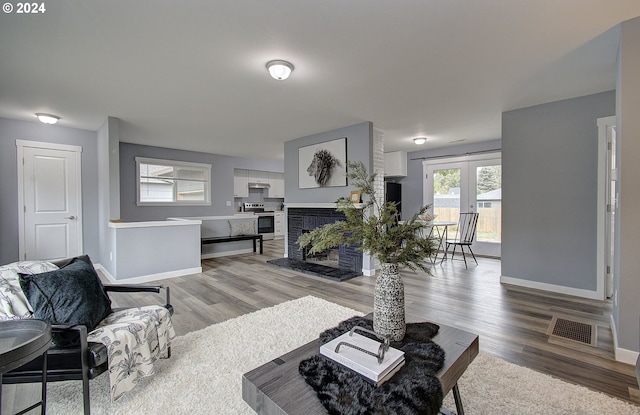 living room featuring french doors, a brick fireplace, and light wood-type flooring