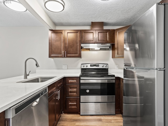 kitchen featuring appliances with stainless steel finishes, sink, light wood-type flooring, a textured ceiling, and dark brown cabinetry