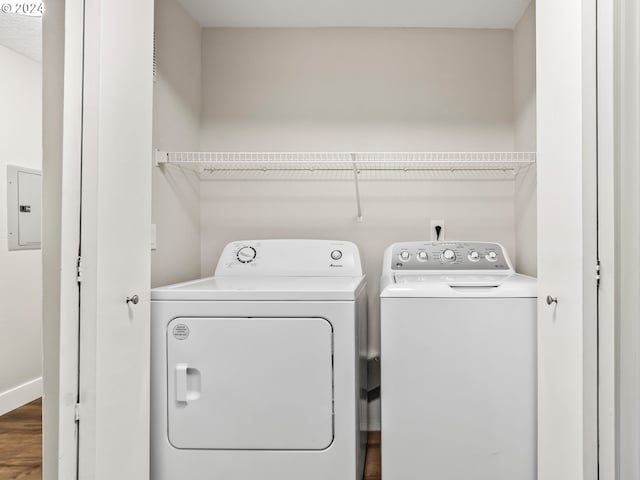 laundry room featuring electric panel, wood-type flooring, and washer and clothes dryer