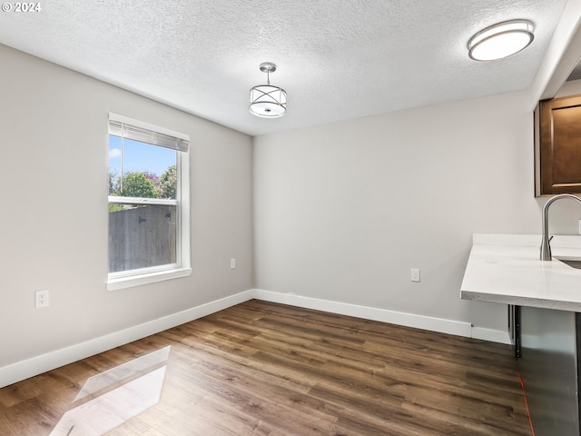 unfurnished dining area featuring dark wood-type flooring and a textured ceiling