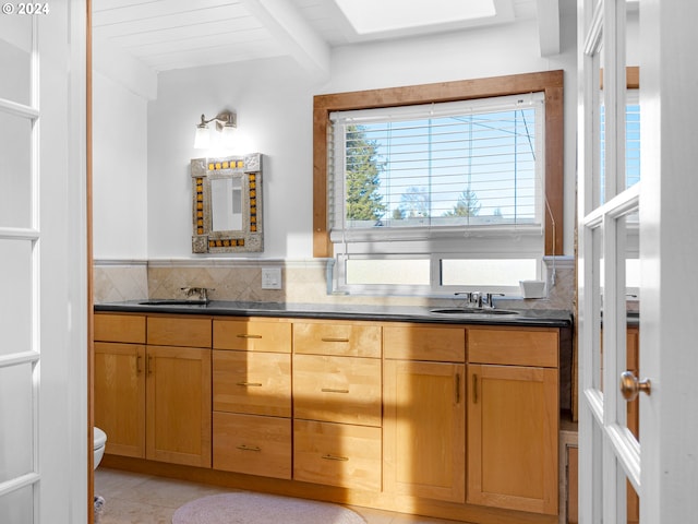 bathroom featuring tile patterned flooring, vanity, vaulted ceiling with beams, and toilet