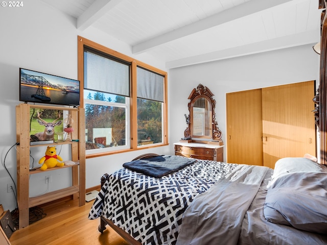 bedroom featuring beam ceiling, light wood-type flooring, and baseboard heating