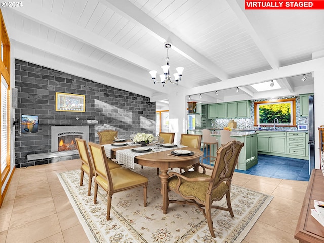 dining area with a tile fireplace, light tile patterned floors, an inviting chandelier, and plenty of natural light