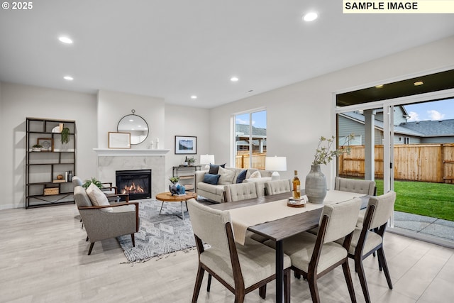 dining area with recessed lighting, light wood-style flooring, baseboards, and a premium fireplace