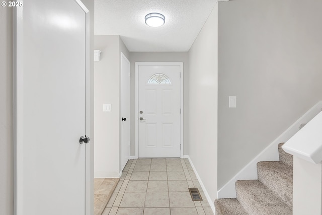 doorway featuring a textured ceiling and light tile patterned flooring