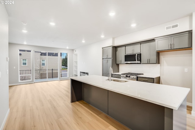 kitchen featuring appliances with stainless steel finishes, a spacious island, visible vents, and light stone counters