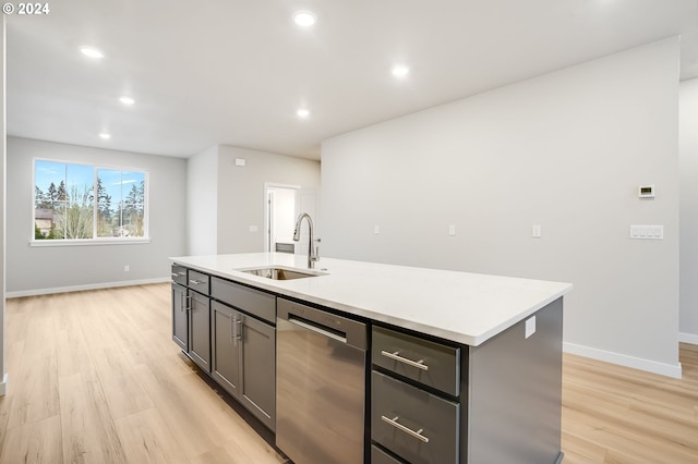 kitchen with light wood-style flooring, a sink, light countertops, dishwasher, and an island with sink